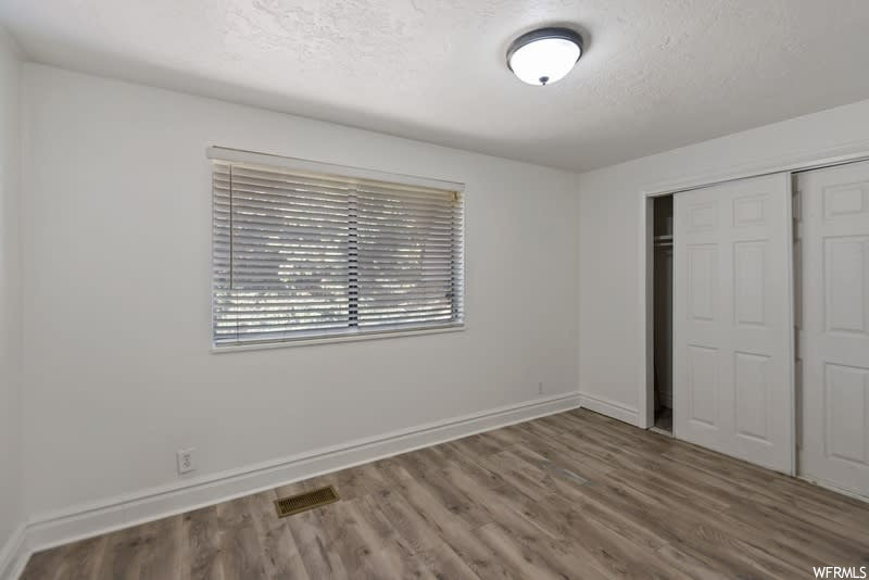 Unfurnished bedroom with dark hardwood / wood-style floors, a closet, and a textured ceiling
