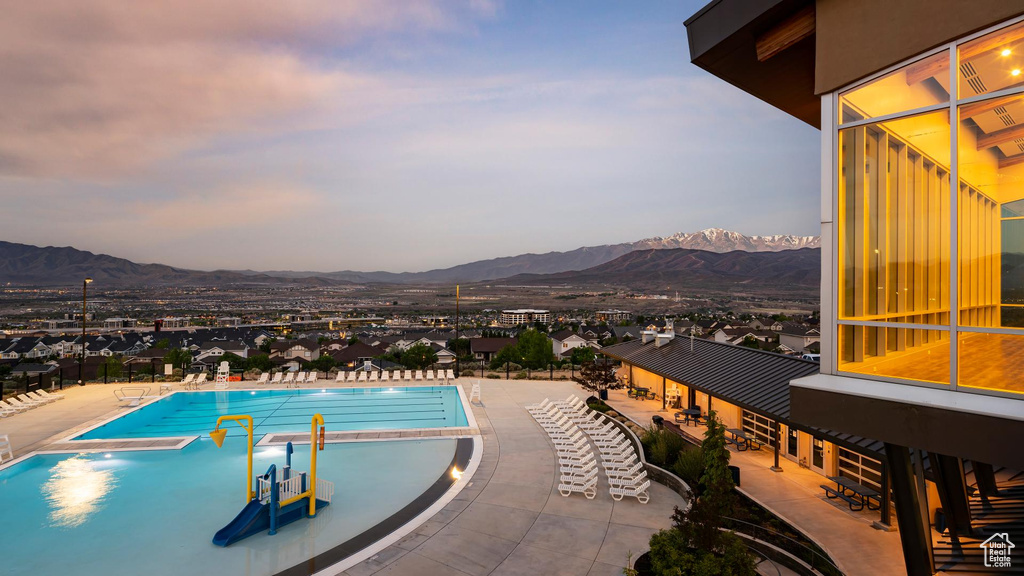 Pool at dusk with a mountain view and a patio