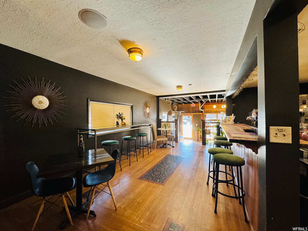 Dining space featuring a textured ceiling, light wood-type flooring, and bar