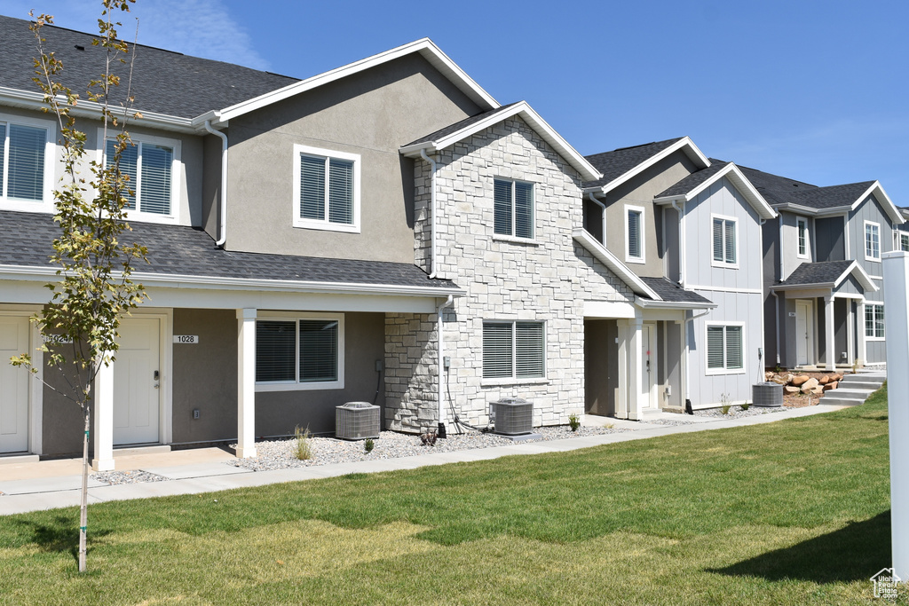 Rear view of property featuring a lawn and central air condition unit