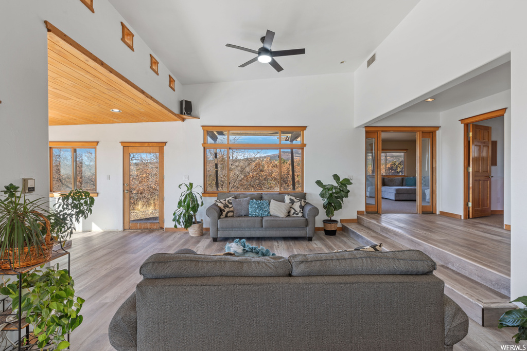 Living room featuring high vaulted ceiling, ceiling fan, and light hardwood / wood-style flooring