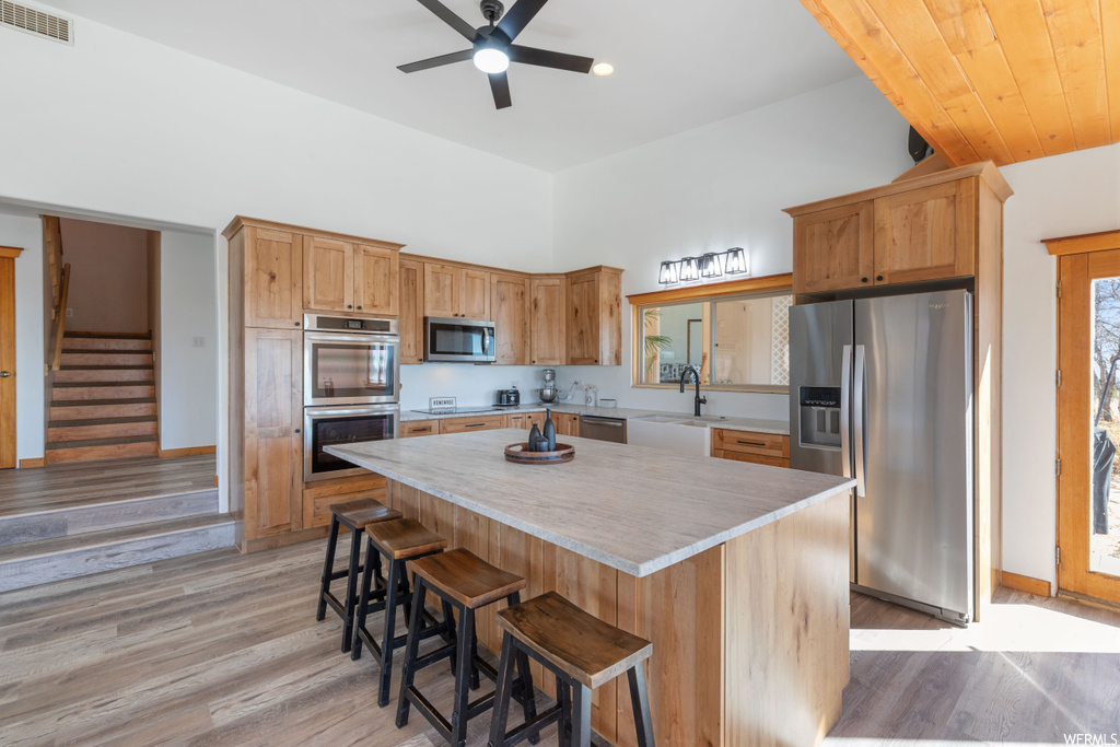 Kitchen with light hardwood / wood-style flooring, ceiling fan, a center island, and stainless steel appliances