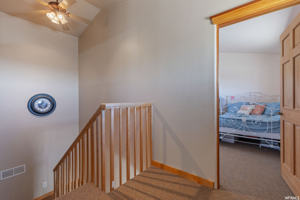 Staircase featuring ceiling fan, carpet flooring, and vaulted ceiling