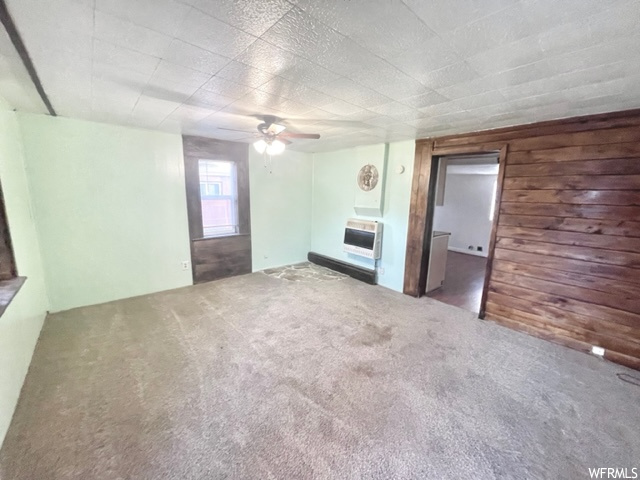Unfurnished bedroom with ceiling fan, dark colored carpet, and a wall mounted air conditioner