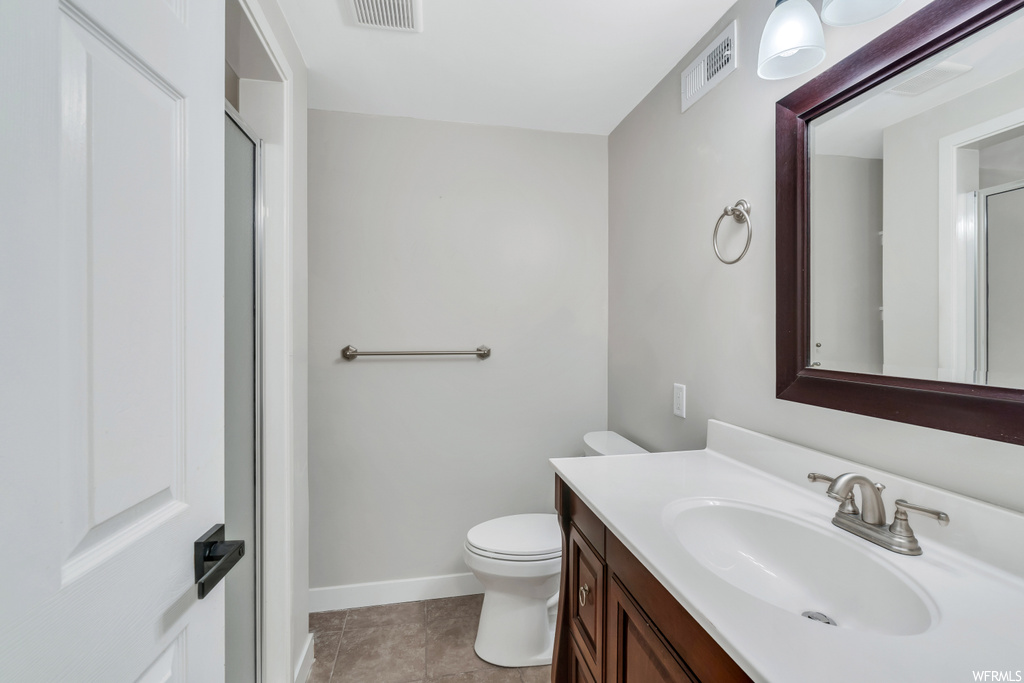 Bathroom featuring toilet, tile flooring, and vanity with extensive cabinet space