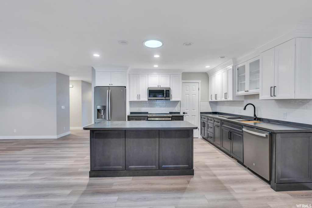 Kitchen featuring tasteful backsplash, light wood-type flooring, and stainless steel appliances
