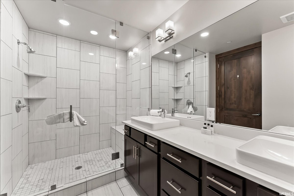 Bathroom with dual vanity, a shower with shower door, and tile flooring