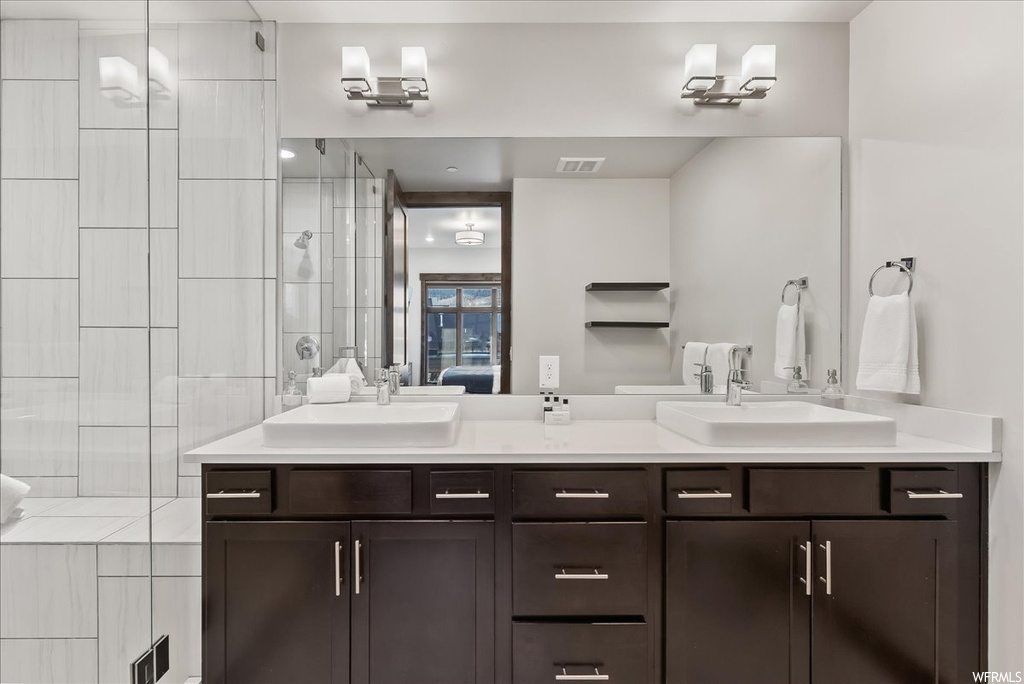 Bathroom featuring double sink vanity and tiled shower