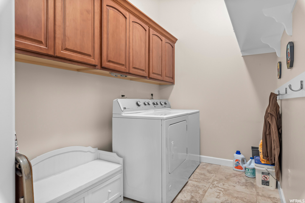 Washroom featuring cabinets, independent washer and dryer, and light tile floors