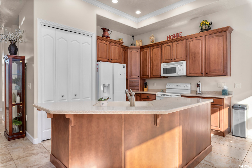 Kitchen with sink, white appliances, light tile flooring, a kitchen island with sink, and a breakfast bar