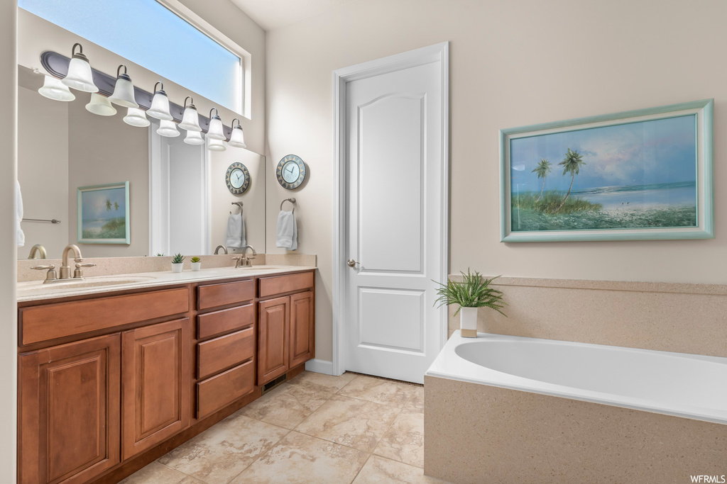 Bathroom featuring tiled bath, tile flooring, and double vanity