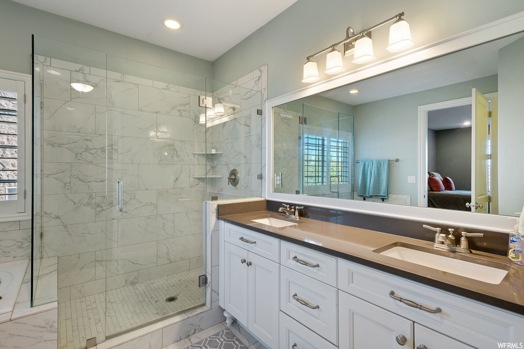 Bathroom featuring a wealth of natural light, double sink vanity, and a shower with shower door