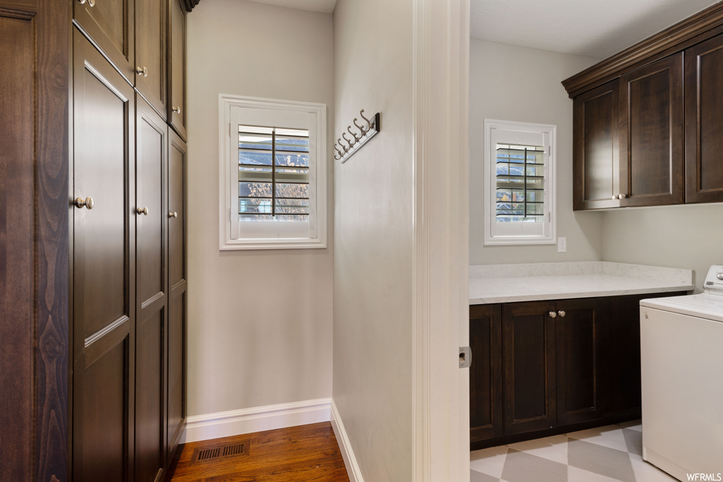 Laundry room featuring light hardwood / wood-style flooring, washer / dryer, and cabinets