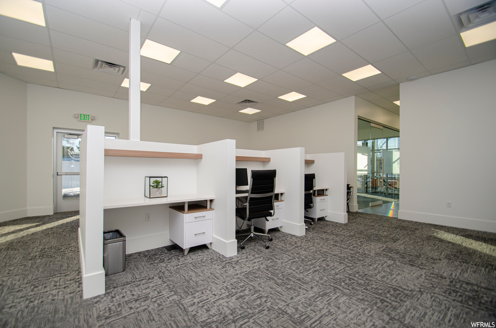 Carpeted office space featuring a towering ceiling and a paneled ceiling