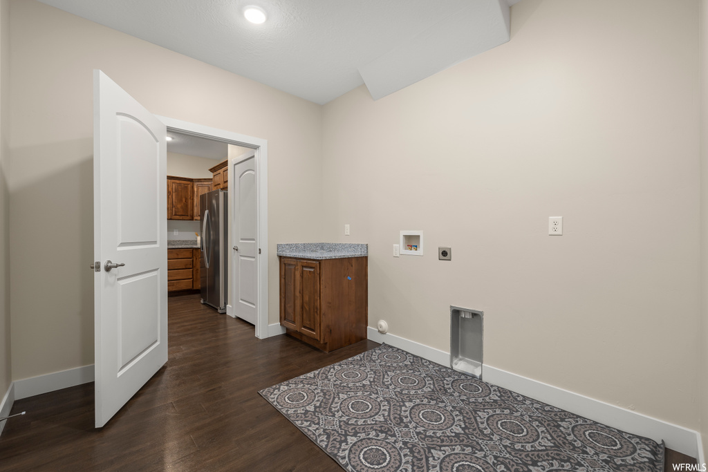 Laundry room with hookup for an electric dryer, hookup for a washing machine, and dark hardwood / wood-style flooring