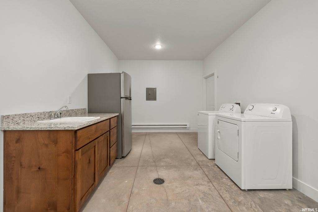 Clothes washing area featuring washing machine and clothes dryer, sink, and a baseboard heating unit