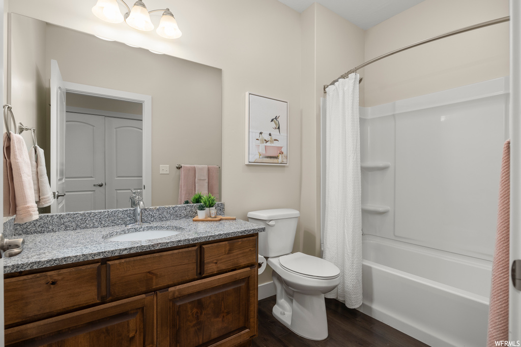 Full bathroom featuring toilet, shower / tub combo, large vanity, and hardwood / wood-style flooring