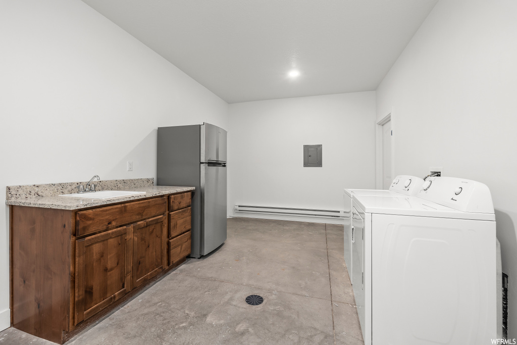 Laundry area featuring a baseboard radiator, sink, and washing machine and dryer