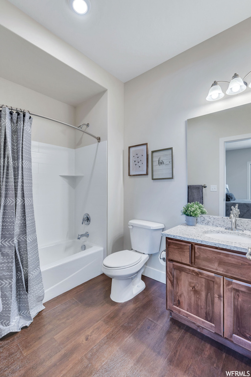 Full bathroom featuring toilet, shower / tub combo, vanity, and hardwood / wood-style floors