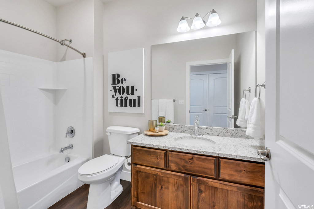 Full bathroom featuring vanity, tub / shower combination, toilet, and hardwood / wood-style flooring