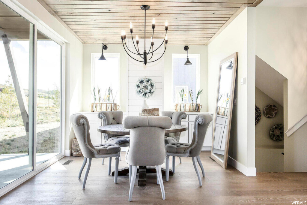 Dining area with an inviting chandelier, wood ceiling, plenty of natural light, and hardwood / wood-style floors