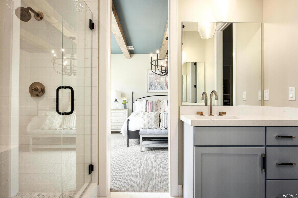 Bathroom with vanity, a shower with door, and an inviting chandelier