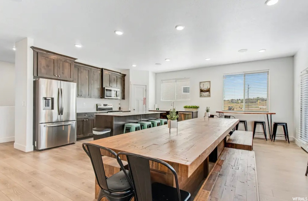 Kitchen featuring a center island, light hardwood / wood-style flooring, stainless steel fridge, range, and dark brown cabinetry