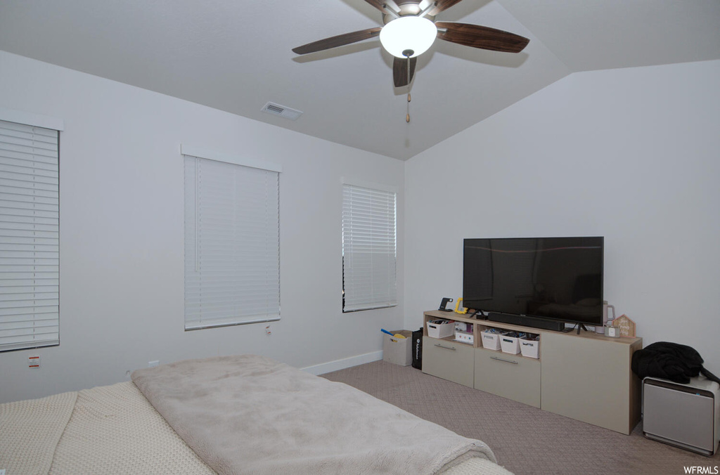 Bedroom featuring vaulted ceiling, ceiling fan, and light carpet