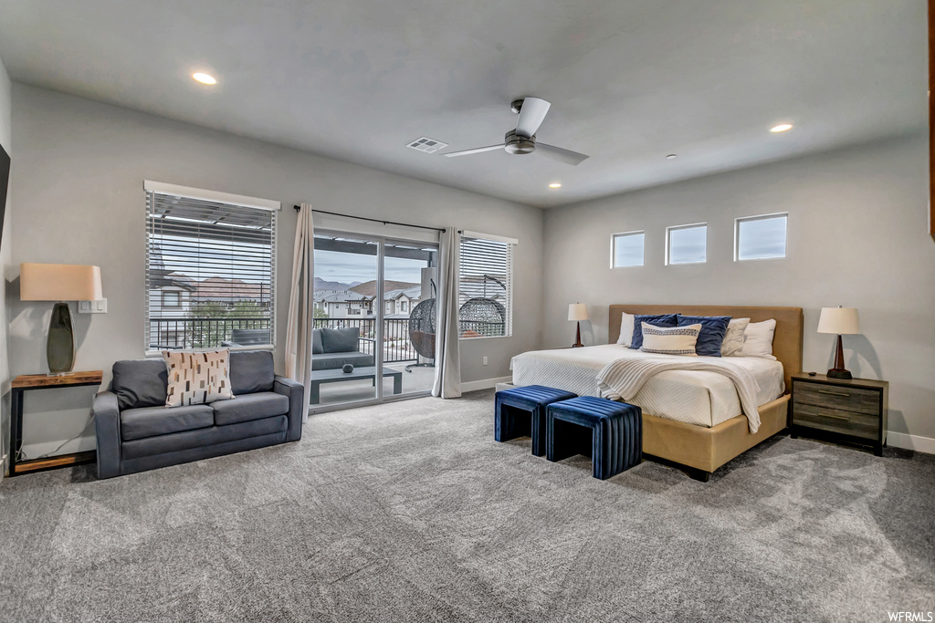 Carpeted bedroom featuring multiple windows, ceiling fan, and access to exterior
