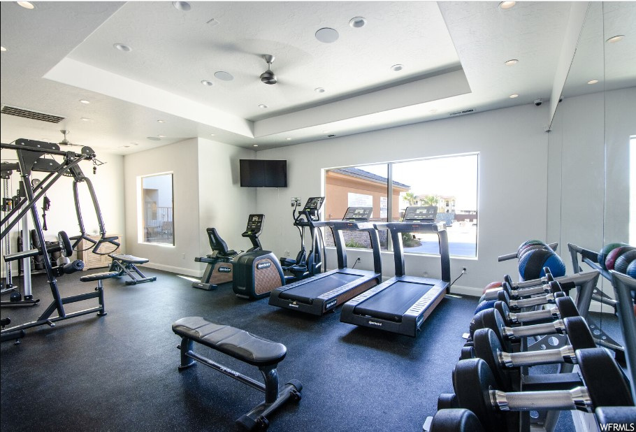 Exercise room with ceiling fan and a tray ceiling