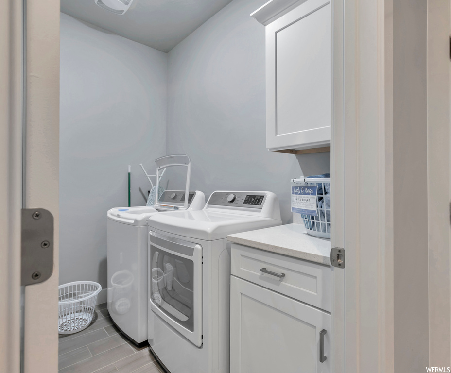 Clothes washing area featuring cabinets and washing machine and clothes dryer