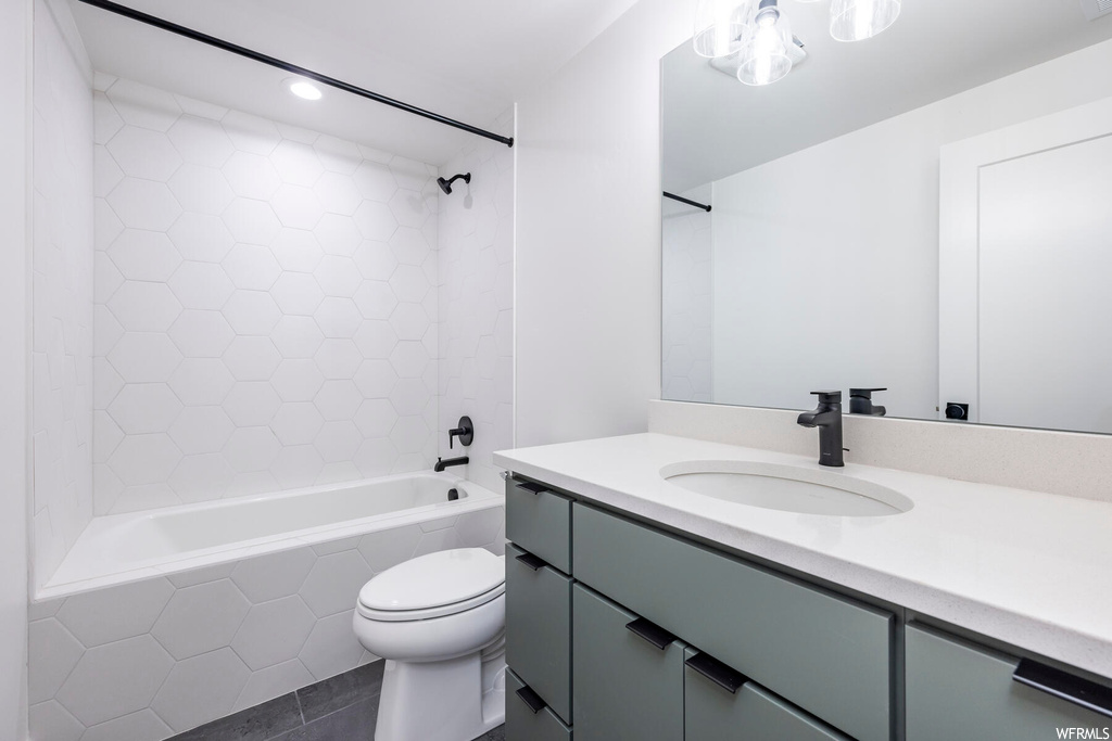 Full bathroom with toilet, tiled shower / bath combo, oversized vanity, and tile flooring