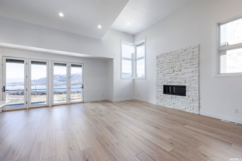 Unfurnished living room featuring a high ceiling, light hardwood / wood-style floors, a fireplace, and a mountain view