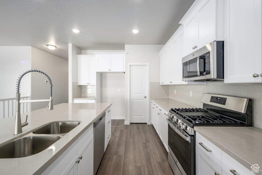 Kitchen featuring dark hardwood / wood-style flooring, stainless steel appliances, backsplash, white cabinets, and sink