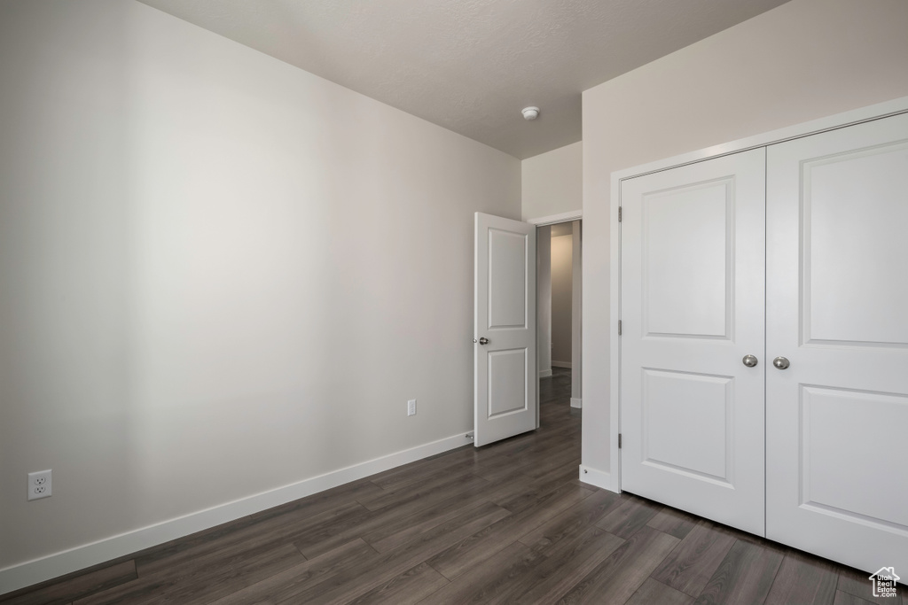 Unfurnished bedroom featuring dark hardwood / wood-style floors and a closet