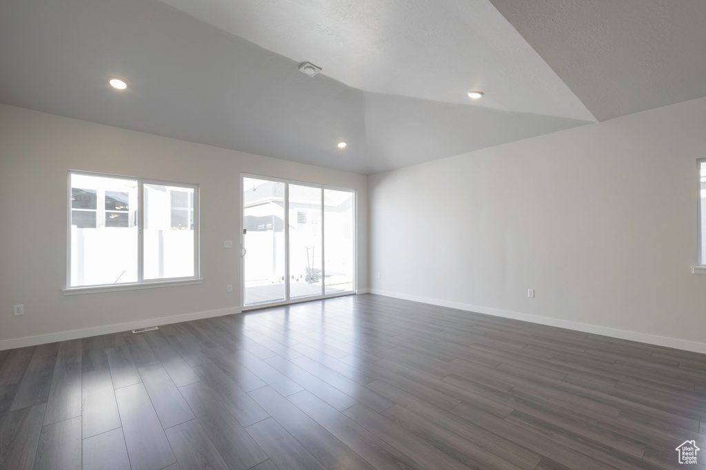 Spare room with vaulted ceiling and dark hardwood / wood-style flooring