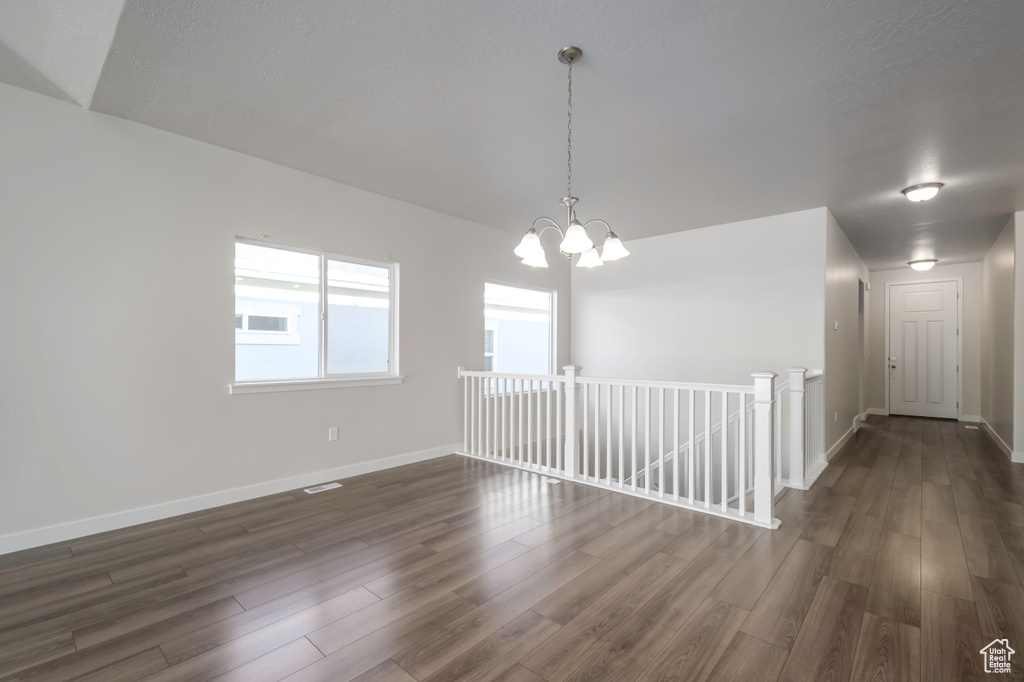 Unfurnished room with dark hardwood / wood-style floors and a chandelier