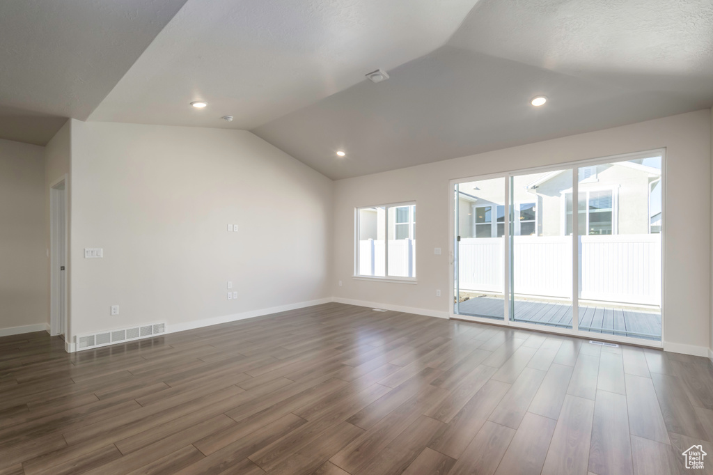 Empty room with vaulted ceiling and dark hardwood / wood-style floors