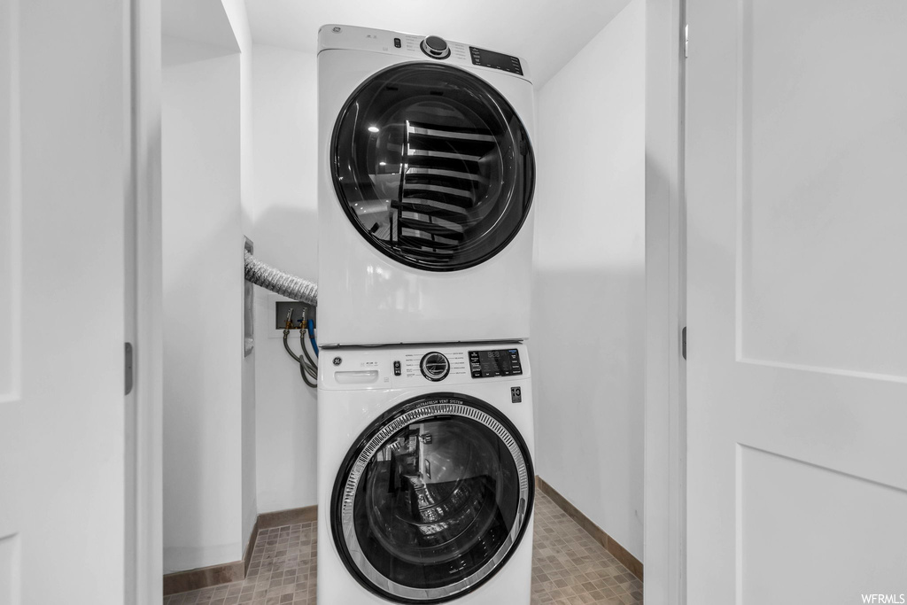 Washroom with washer hookup, light tile flooring, and stacked washer and clothes dryer