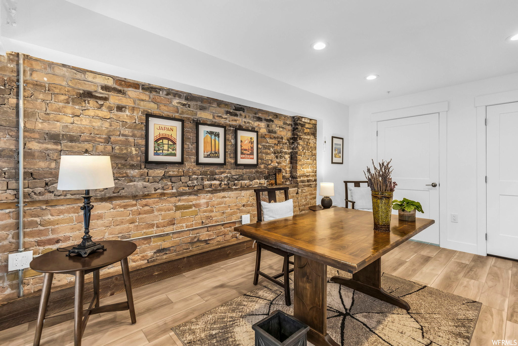 Dining space with light hardwood / wood-style flooring and brick wall