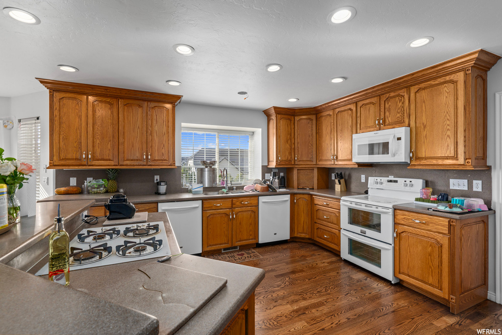Kitchen featuring white appliances, dark hardwood / wood-style flooring, and sink