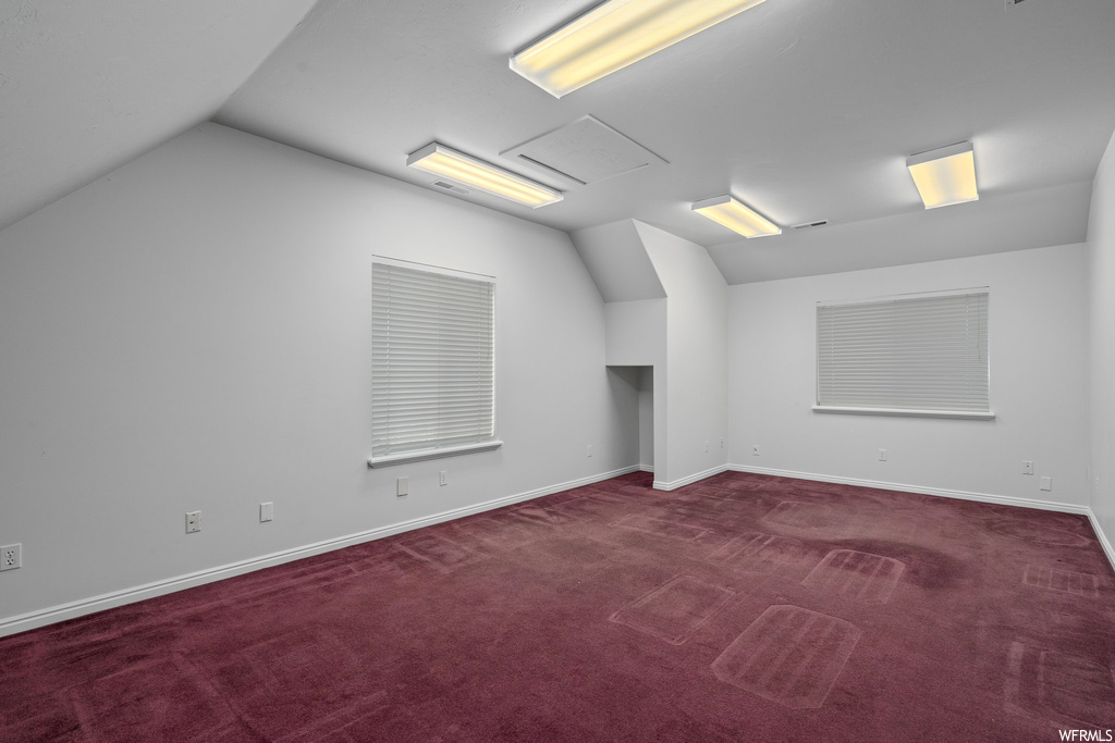 Empty room with lofted ceiling and dark colored carpet