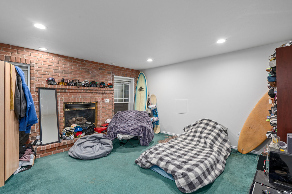 Bedroom featuring dark colored carpet, a brick fireplace, and brick wall
