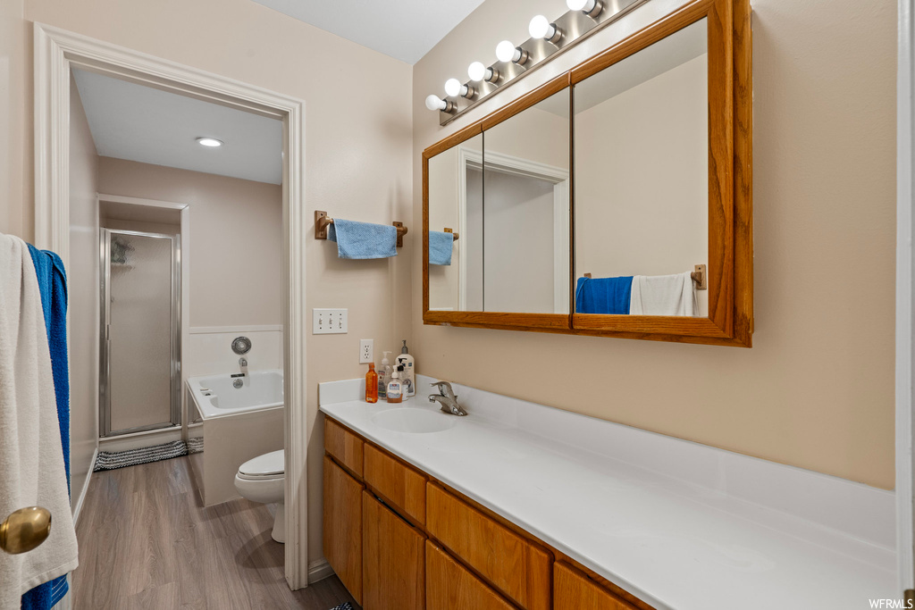 Full bathroom featuring independent shower and bath, vanity, toilet, and hardwood / wood-style flooring
