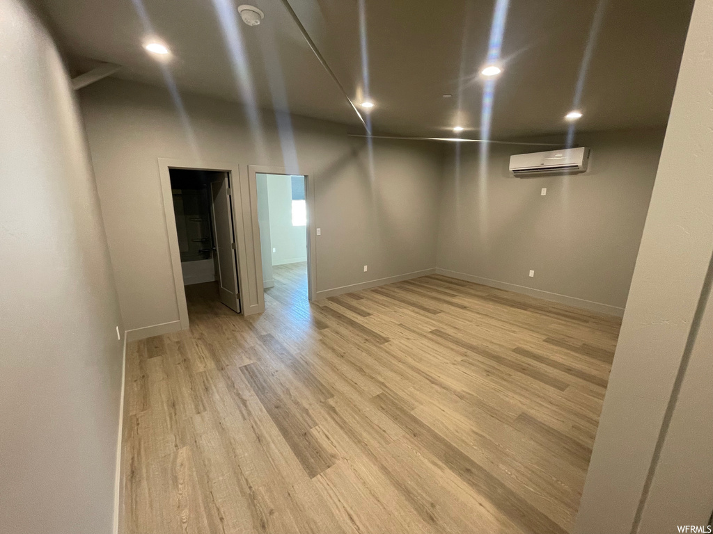 Basement featuring light hardwood / wood-style floors and a wall mounted air conditioner