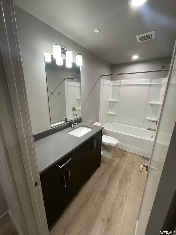Full bathroom featuring toilet, vanity, washtub / shower combination, and hardwood / wood-style flooring
