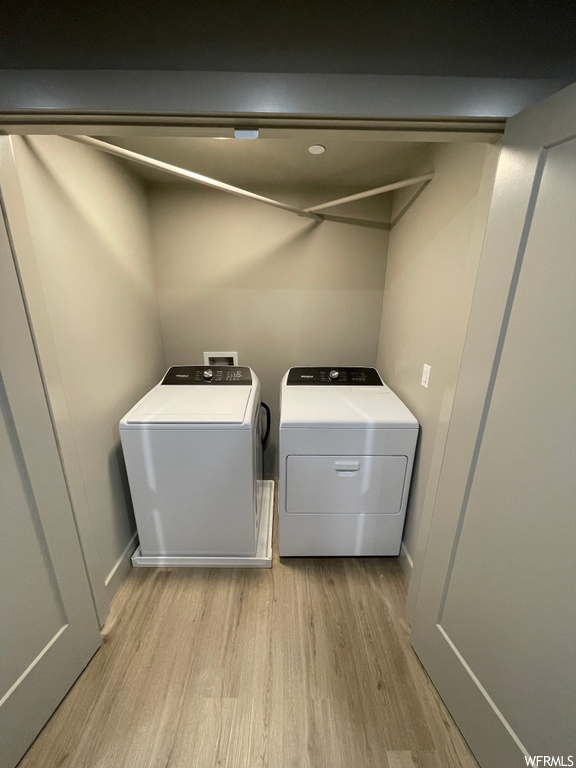 Laundry room with light hardwood / wood-style flooring, washing machine and clothes dryer, and washer hookup