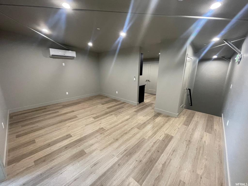 Basement featuring light hardwood / wood-style flooring and a wall unit AC