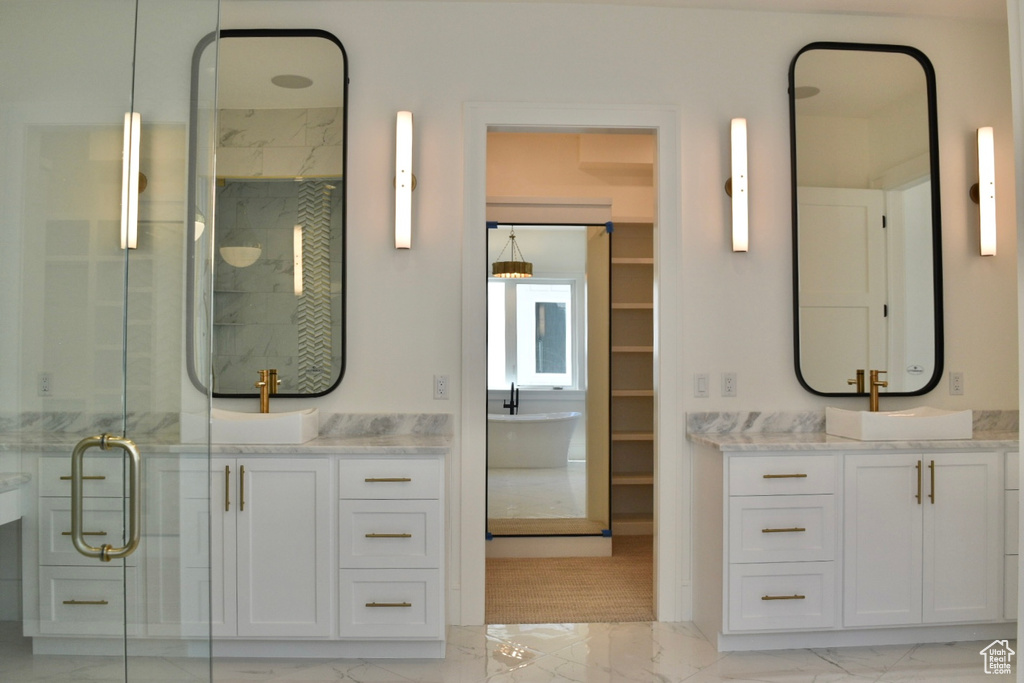 Interior space with a shower with shower door, dual bowl vanity, and tile patterned floors