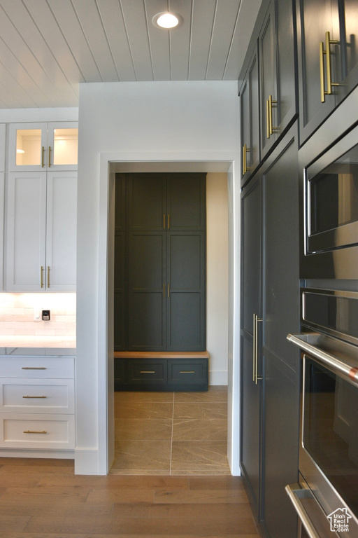 Kitchen with appliances with stainless steel finishes, light hardwood / wood-style floors, and white cabinetry